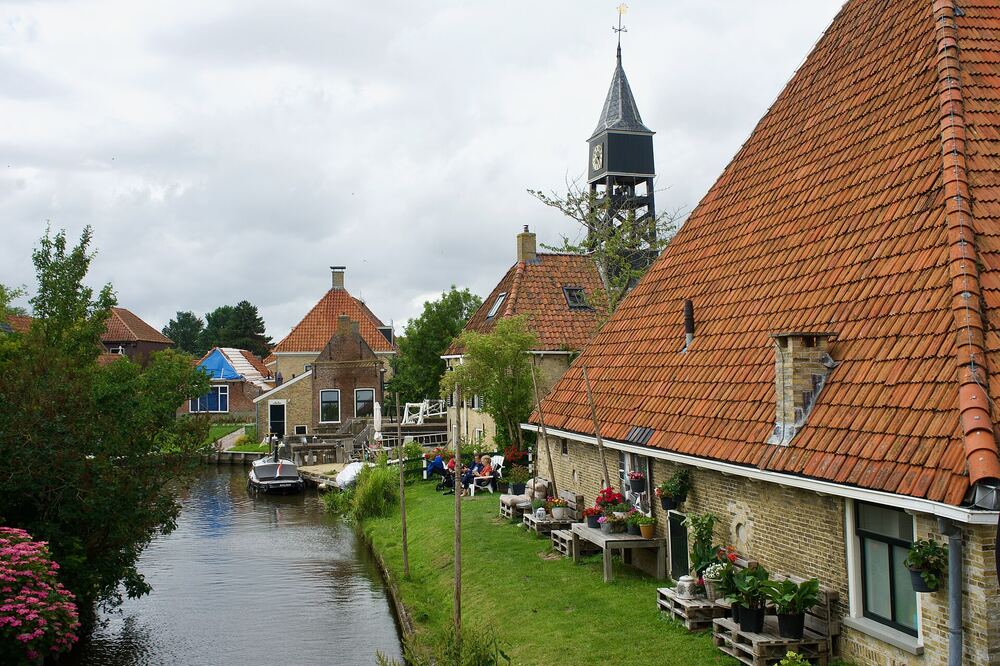 Smalle vaart in Hindeloopen met oude huizen en de houten klokkentoren op de achtergrond